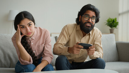 Diverse multiethnic couple at home bored angry arabian woman offend on husband addicted playing...