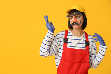 Funny young female decorator with gloves on orange background. Fool's day