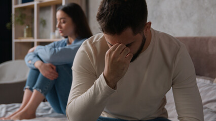 Annoyed Caucasian husband sit apart on bed with offended wife keep silence after fight family...