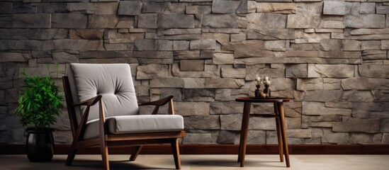 A wooden chair and table placed in front of a textured stone wall. The simple furniture contrasts with the rough surface of the wall, creating a striking visual composition.