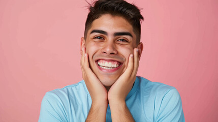 close-up of a young man with a joyful and surprised expression, hands on his cheeks, against a vibrant pink background.