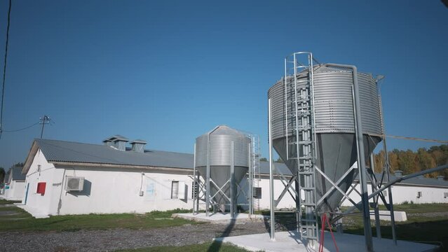 Two silo towers used for storage of food for animals at the farming facility. Storage of the barley grain seeds inside the silo towers. Storage of bird feed in the Steel silo tower