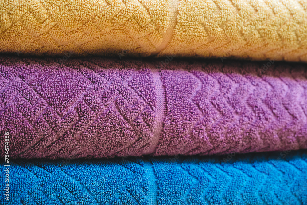 Fototapete multi-colored textile towels lie in a stack on a shelf