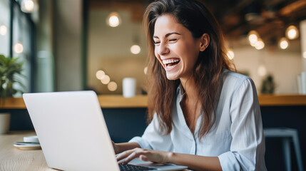 Woman working on a laptop and laughing in the office