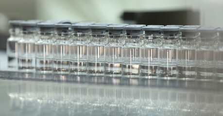 A lot of liquid vaccine injection medicine filled glass vials enter into lyophilization chamber for...