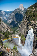 Waterfall with a rainbow in yosemite with half dome in background
