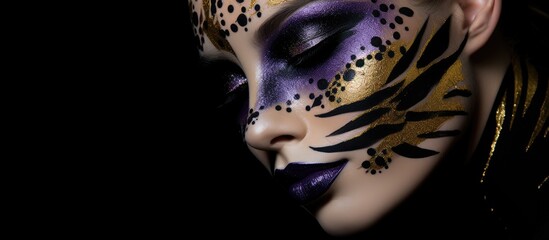 A close-up view of a beautiful girl with creative black, purple, and gold face paint, against a black background in a studio setting.