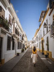Beautiful woman tourist from the back walking on the street of San Basilio in Cordoba