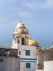 Fototapeta na wymiar Tower of the Cathedral of Cadiz (Catedral de la Santa Cruz de Cádiz), as seen from the narrow street