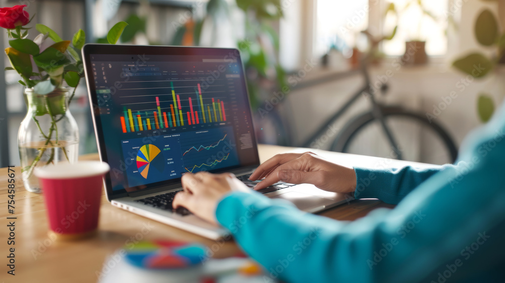 Poster close-up of a person's hand using a laptop with financial charts and graphs displayed on the screen
