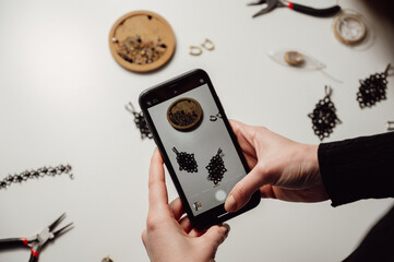 side view on Creative jewellery artist is taking photo of handmade earrings with smartphone