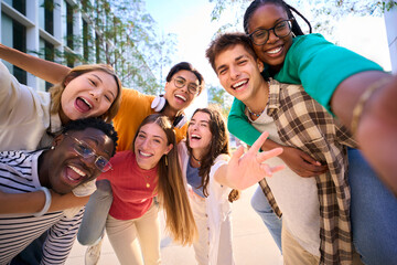A large multiracial group of teenagers taking a selfie looking front camera laughing and having fun...