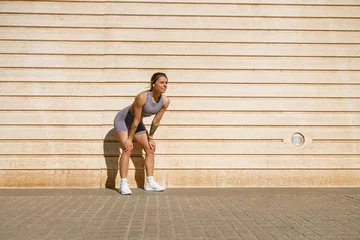 Fotobehang Female athlete in sportswear have a rest after morning jogging outside and looks away © Yaroslav Astakhov