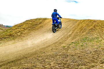 Person riding motocross bike on dirt road with helmet