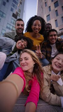 Vertical. A group of happy people is sharing a fun moment. Young friends take a selfie picture during a leisure event. The team is traveling together. Smiling community portrait looking at camera