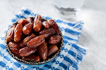 Medjool Dates Bowl and Glass of Water on Concrete Background, Healthy Ramadan Suhour Snack, Close-up