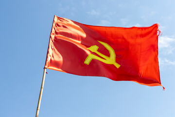 Large communist flag floating in the wind with a blue sky