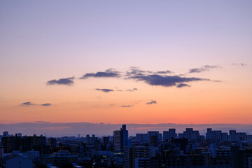 Fototapeta premium 都市の夜明け。神戸市から芦屋大阪方面をのぞむ。生駒の山並みから朝日が昇る。都市のビルがシルエットで浮かぶ。