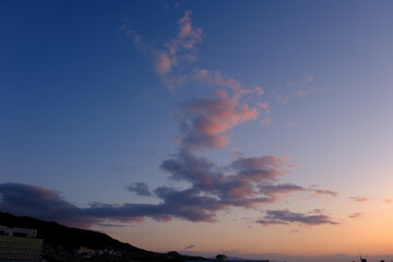 都市の夜明け。神戸市から芦屋大阪方面をのぞむ。生駒の山並みから朝日が昇る。都市のビルがシルエットで浮かぶ。