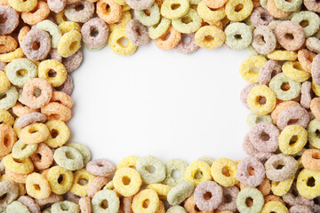 Frame made of tasty cereal rings on white background, top view. Space for text