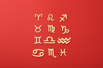 Zodiac signs on red background, flat lay