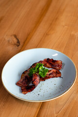 Fried bacon on a plate with greens.