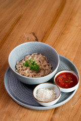 Pasta, garnished with a sprig of parsley in a bowl, served with grated cheese and tomato paste.