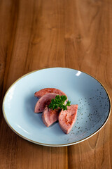 Pieces of fried sausage on plates decorated with herbs.