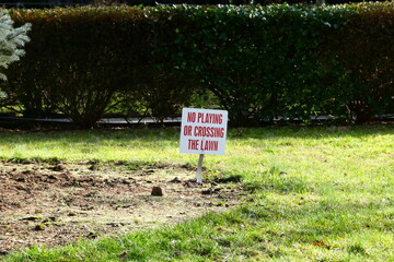 A sign in the middle of a grass patch on a sunny day