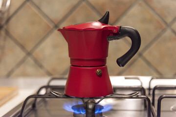 Red metal geyser coffee maker on a gas stove - moka, brew coffee, home cooking, Italian traditions,...