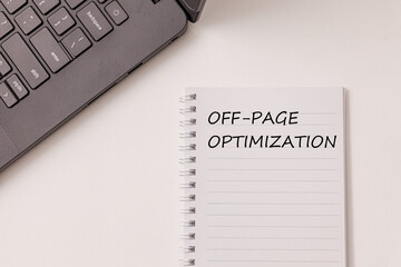 Black laptop and notebook have text Off-page Optimization on the white desk. Concept improve...