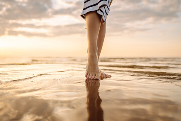 Close- up leg of young woman walking along wave of sea water and sand on the summer beach. Travel,...