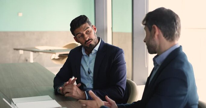 Two men business partners, Indian and Portuguese businessmen in suits negotiate, met in boardroom, engaged in business strategy discussion, share professional opinion, consider plan, talk about goals