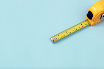 The yellow measuring tape for the mason is placed on a blue background. Soft focus.