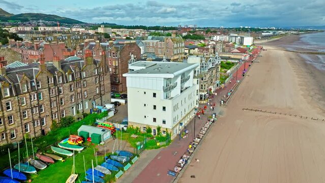 Aerial view of Portobello Beach, traditional seaside pursuits on the prom with sandy stretches of beach overlooking the Forth. Beach next to Edinburgh features a promenade with historical buildings.