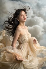 Ethereal Woman in Flowing Beige Dress with Windswept Hair against Dramatic Cloudy Sky