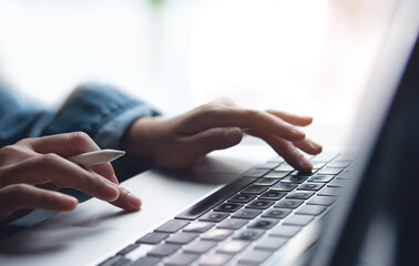 Closeup of business woman hand typing and working on laptop computer, searching the information, surfing the internet with digital tablet on office table, remote work, online job concept