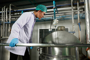 worker looking and checking water on large industrial pot in the factory