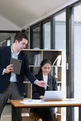 Photo of two business people using laptop computer and working together in the office desk.