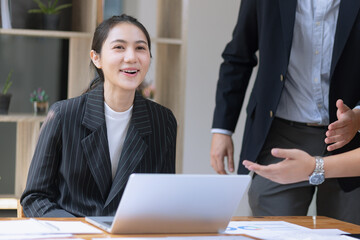 Photo of two business people using laptop computer and working together in the office desk.