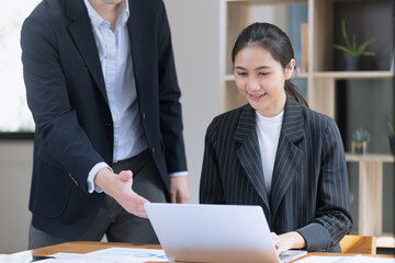 Photo of two business people using laptop computer and working together in the office desk.
