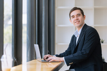 Businessman working on laptop sitting at desk in office.