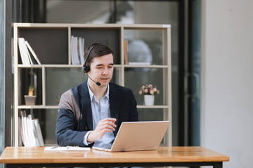 Fototapeta premium Businessman using laptop with earphones and working at desk in the office.