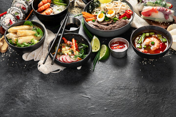 Traditional Asian food table. Spring roll, rice, shrimp, sushi, vegetables, meat on dark background