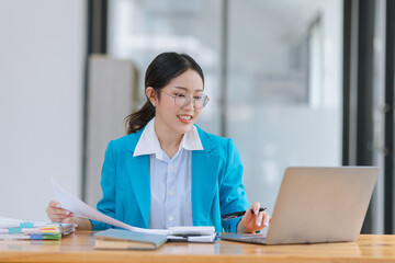 Asian accounting woman working with document paper and laptop computer at table office, Financial and accounting woman concept. 