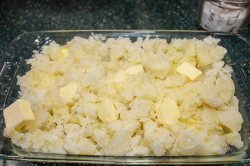 View of a casserole dish with potatoes and butter for making mashed potatoes.
