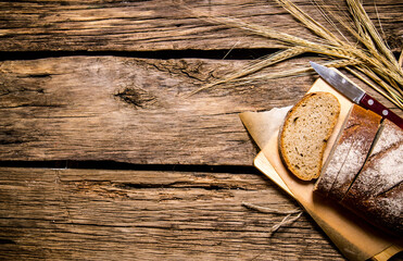 Fresh bread with ears of rye. On wooden table.