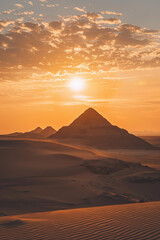 A pyramid in a desert during the sunset