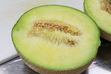 半分にカットした果汁たっぷりの緑のメロンと種子