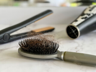 Low angle view of hair brush with lots of hair on it after brushing it and styling it, with hot...